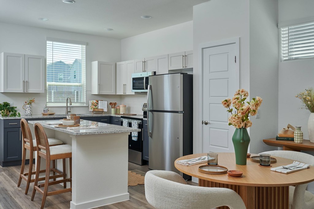 A kitchen with a refrigerator, table, and chairs.