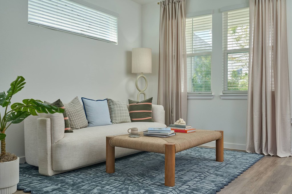 A living room with a white couch, a wooden coffee table, and a potted plant.