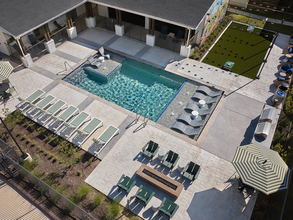 A pool with sun loungers and a table.