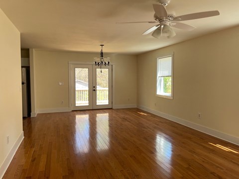 an empty living room with wooden floors and a ceiling fan