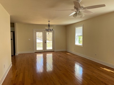 an empty living room with wooden floors and a ceiling fan