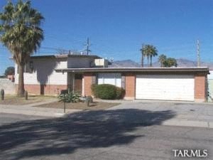 a house with two garage doors and palm trees