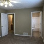 an empty room with a ceiling fan and a door to a bathroom