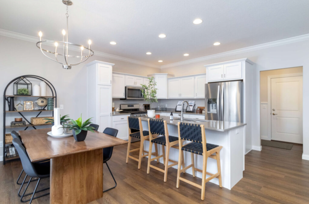 a kitchen and dining room with white cabinets and a wooden table