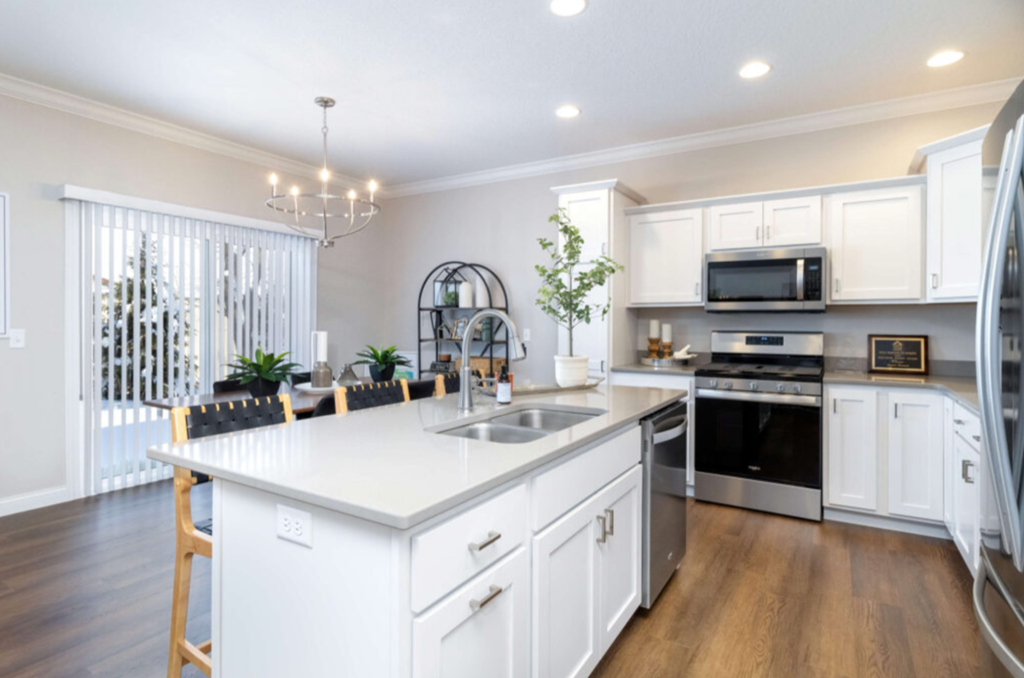 a white kitchen with a large island and stainless steel appliances