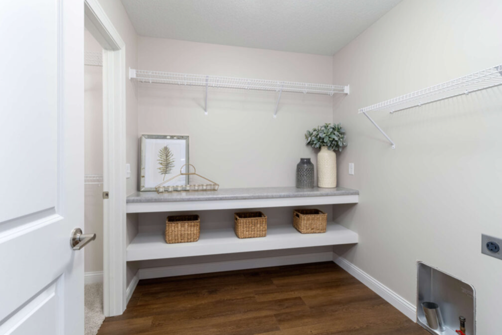 a walk in closet with white walls and shelves with baskets and a vase
