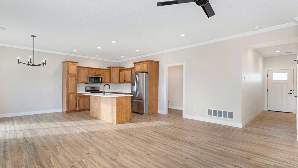 an empty kitchen and living room with wooden floors and wooden cabinets