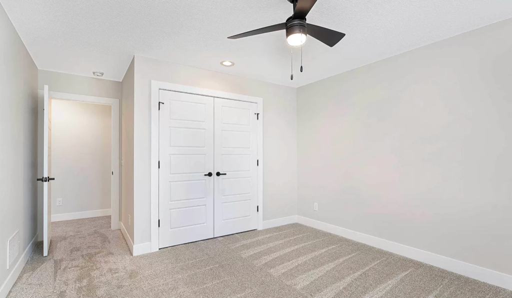 an empty room with a ceiling fan and a closet