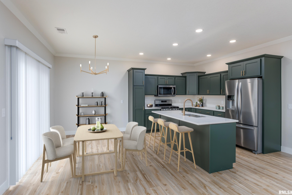 a kitchen and dining area with green cabinets and a stainless steel refrigerator