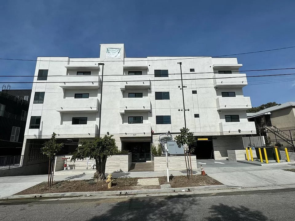 A white building with a black railing in front of it.