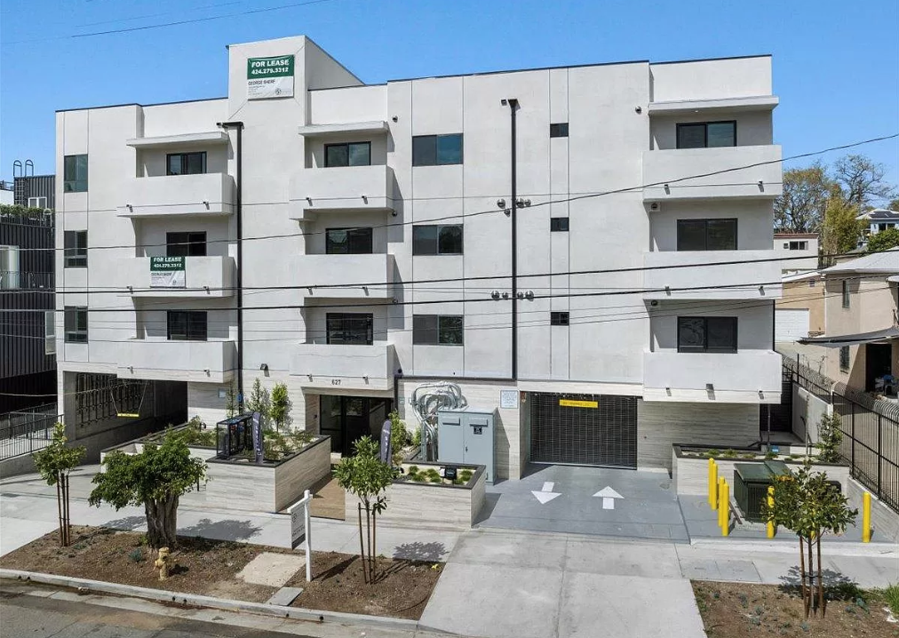 A white building with a green sign on the top left corner.