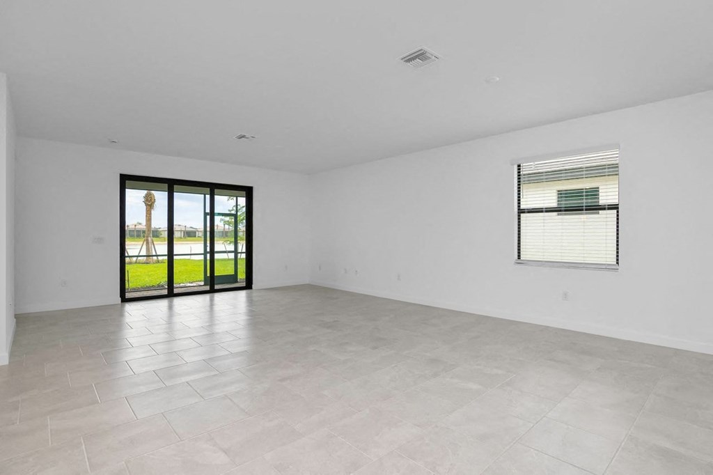 an empty living room with a sliding glass door to a yard