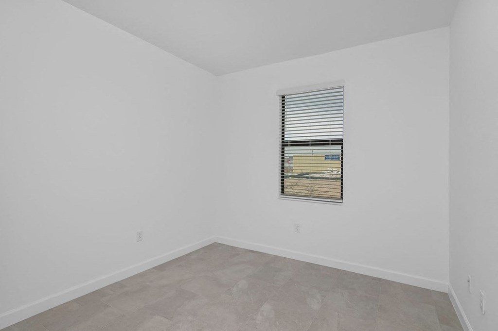 an empty room with a window and white walls
