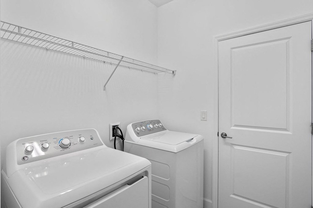 a white laundry room with two washes and a dryer