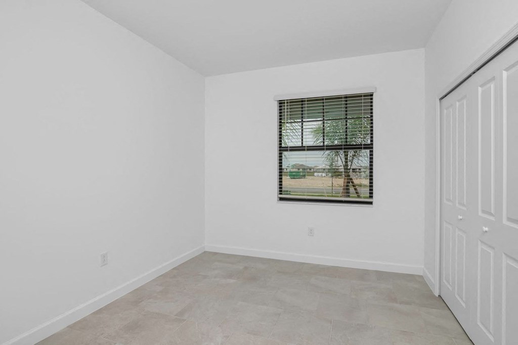 an empty bedroom with a window and a door