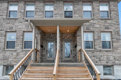 the front of a stone building with two doors and a porch