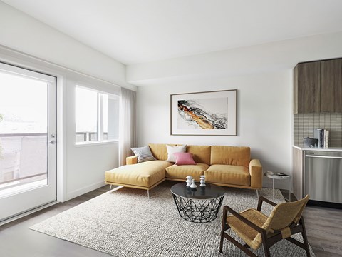 A living room with a yellow sofa, a coffee table, and a painting on the wall.