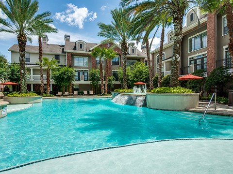 A swimming pool surrounded by palm trees and buildings.