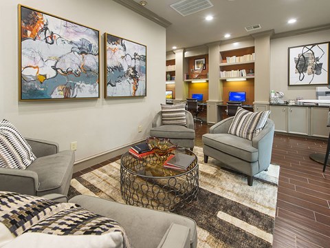 A living room with a grey couch, a coffee table, and two paintings on the wall.