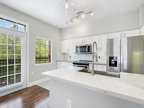 A kitchen with white cabinets and a white counter top.