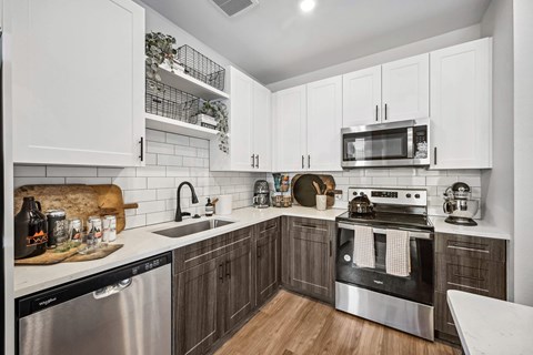 A modern kitchen with white cabinets and stainless steel appliances.