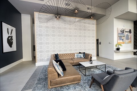 A living room with a brown couch and a patterned wallpaper.
