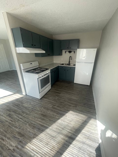 an empty kitchen with white appliances and blue cabinets