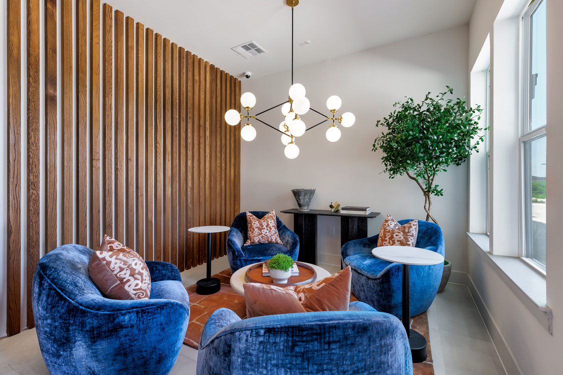 A living room with blue chairs and a wooden wall.