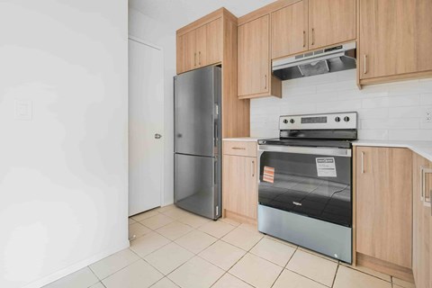 A kitchen with a refrigerator, oven, and cabinets.