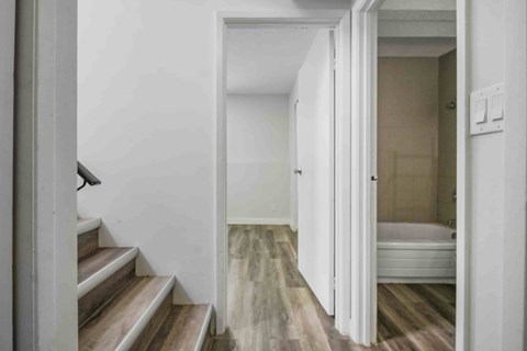 A white room with a bed and a staircase.