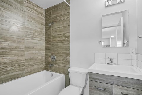 A bathroom with a white tub, toilet, and sink.