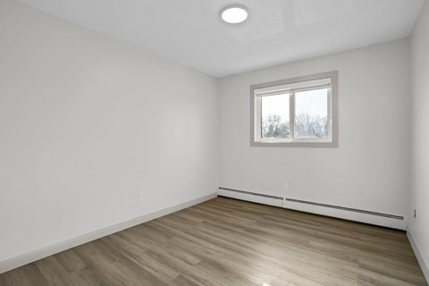 A room with a window and wooden flooring.