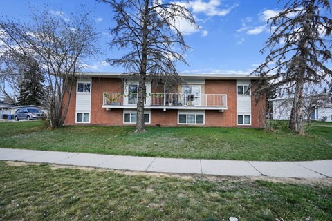 A two-story apartment building with a red brick exterior and white trim.