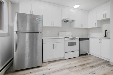 A kitchen with a stainless steel refrigerator and white cabinets.