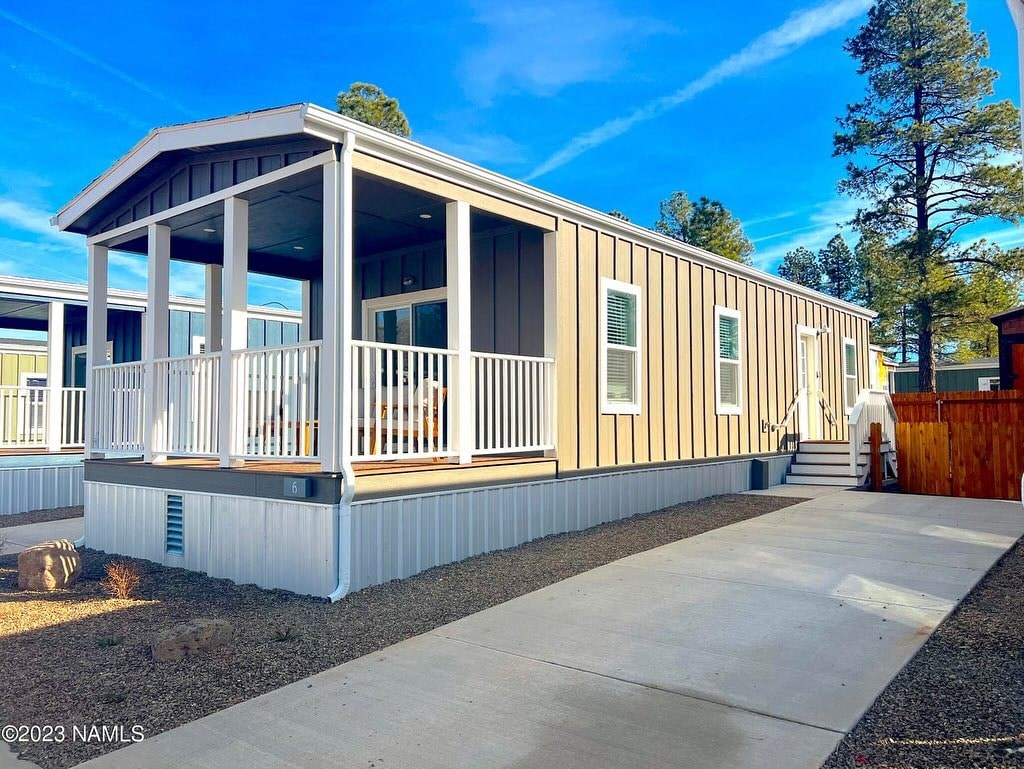 a white and yellow house with a porch and a driveway
