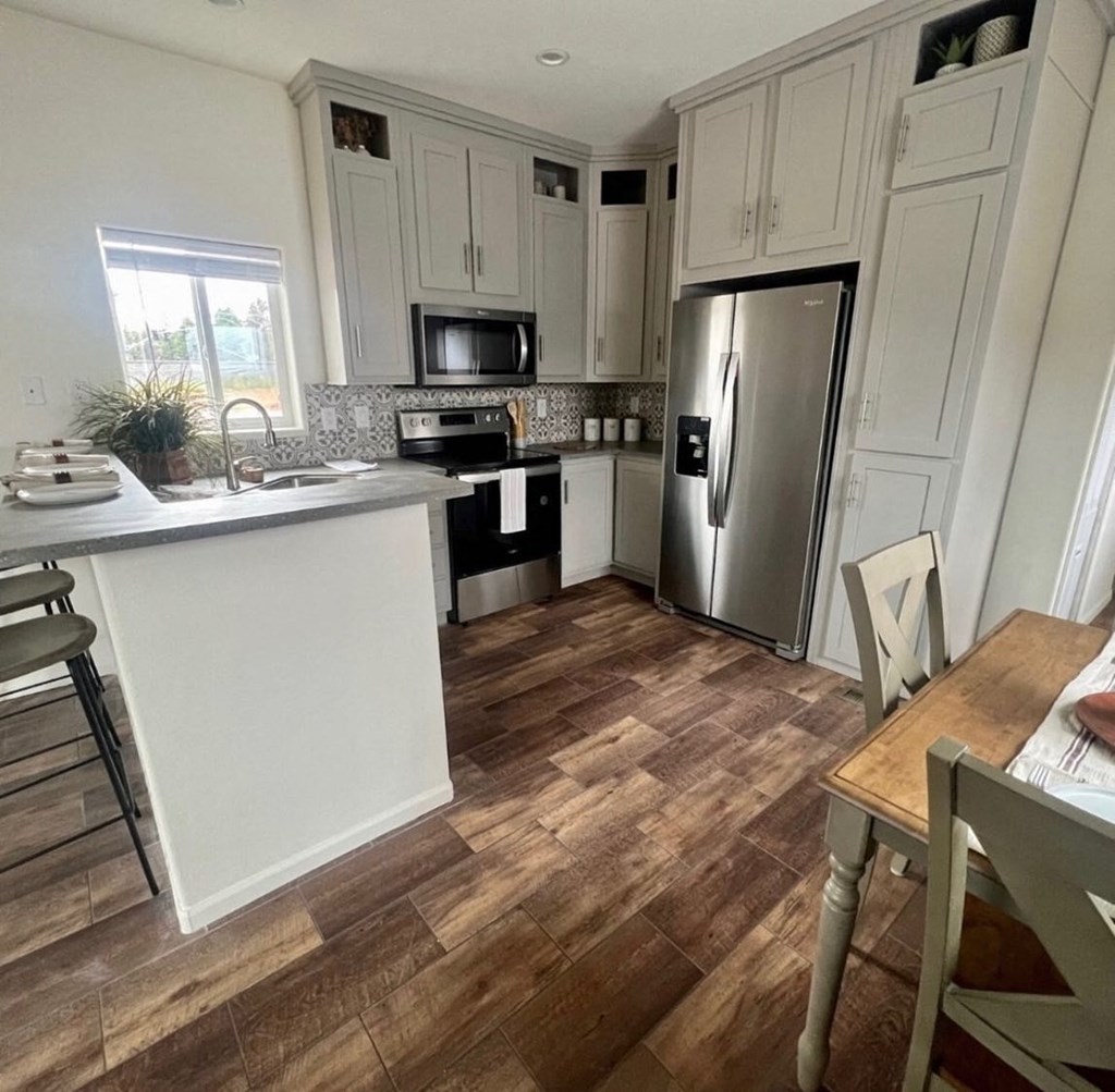 a kitchen with white cabinets and a stainless steel refrigerator
