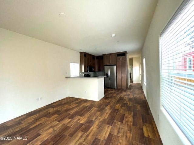 an empty living room and kitchen with wood flooring