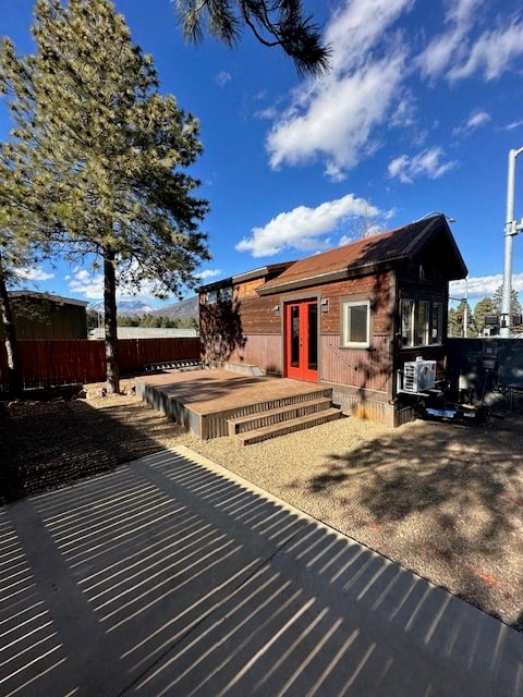 a small house with a deck and a tree