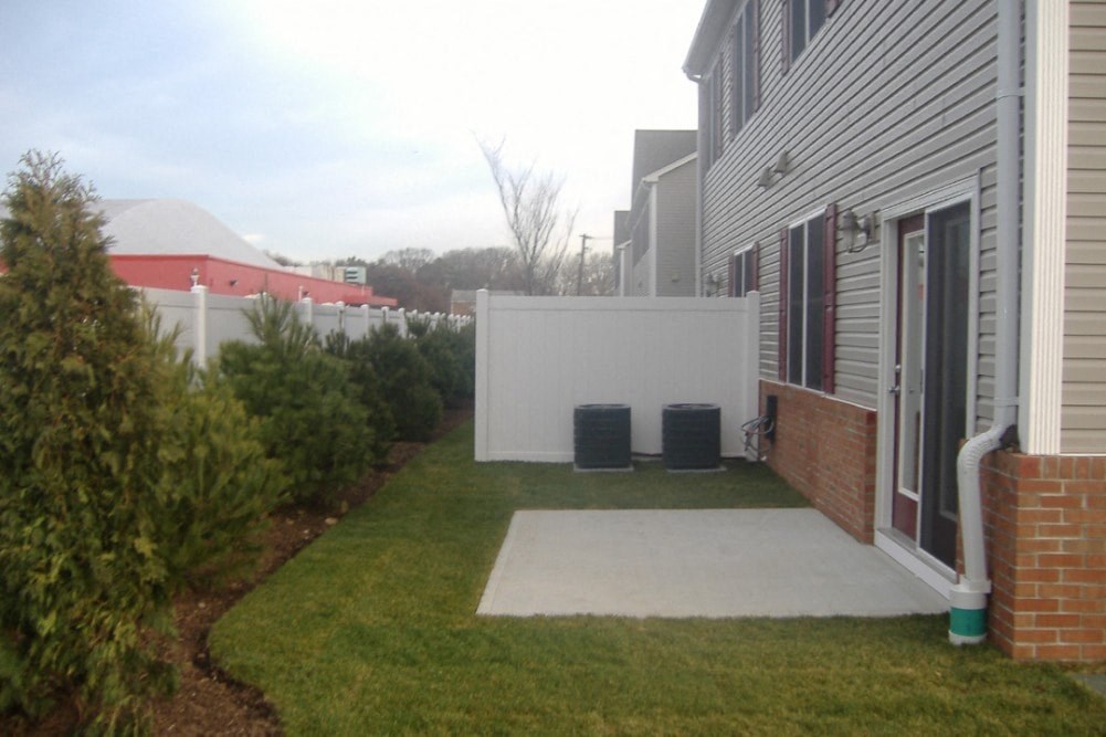 the back yard of a house with a white fence and a patio and grass
