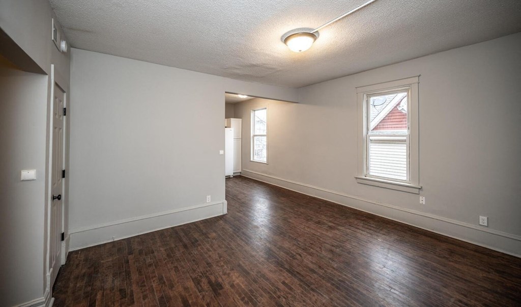 the living room and dining room of an empty house with wood flooring