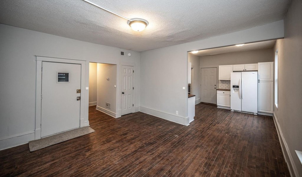 an empty living room and kitchen with a wood floor