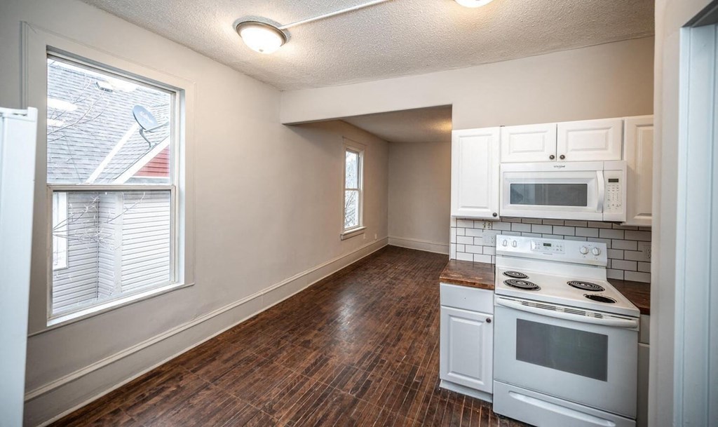 an empty kitchen with white appliances and a window