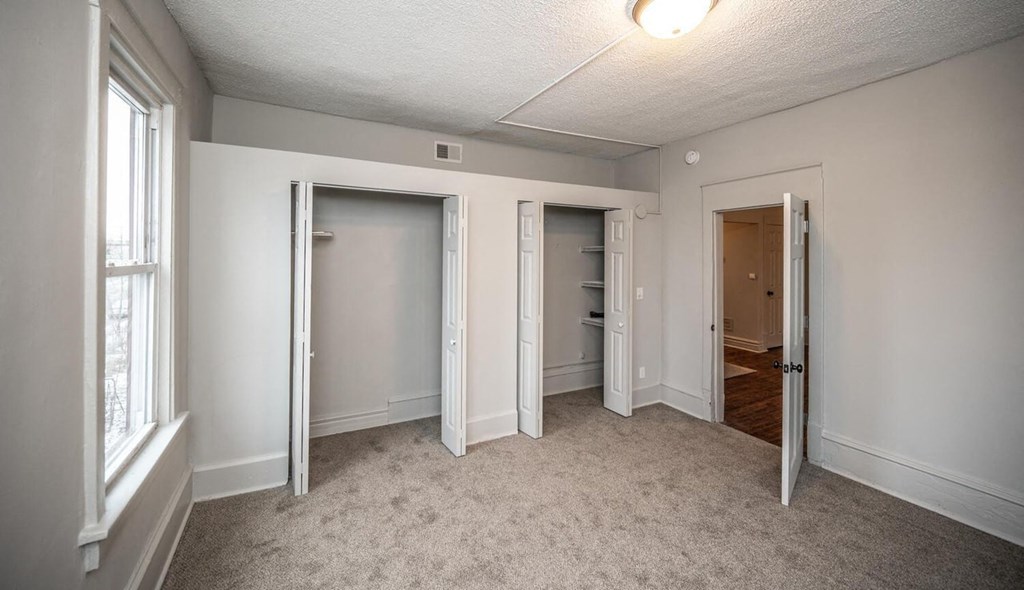 a bedroom with three closets and a door to the bathroom