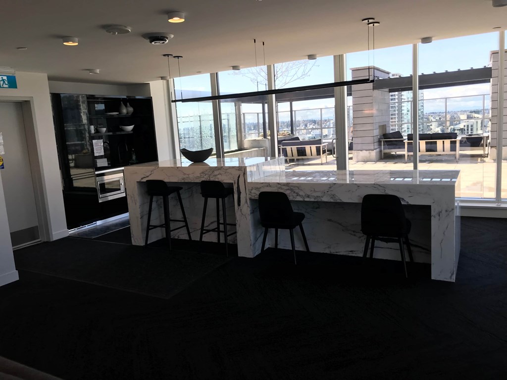 a kitchen with a marble counter and chairs in a room with large windows