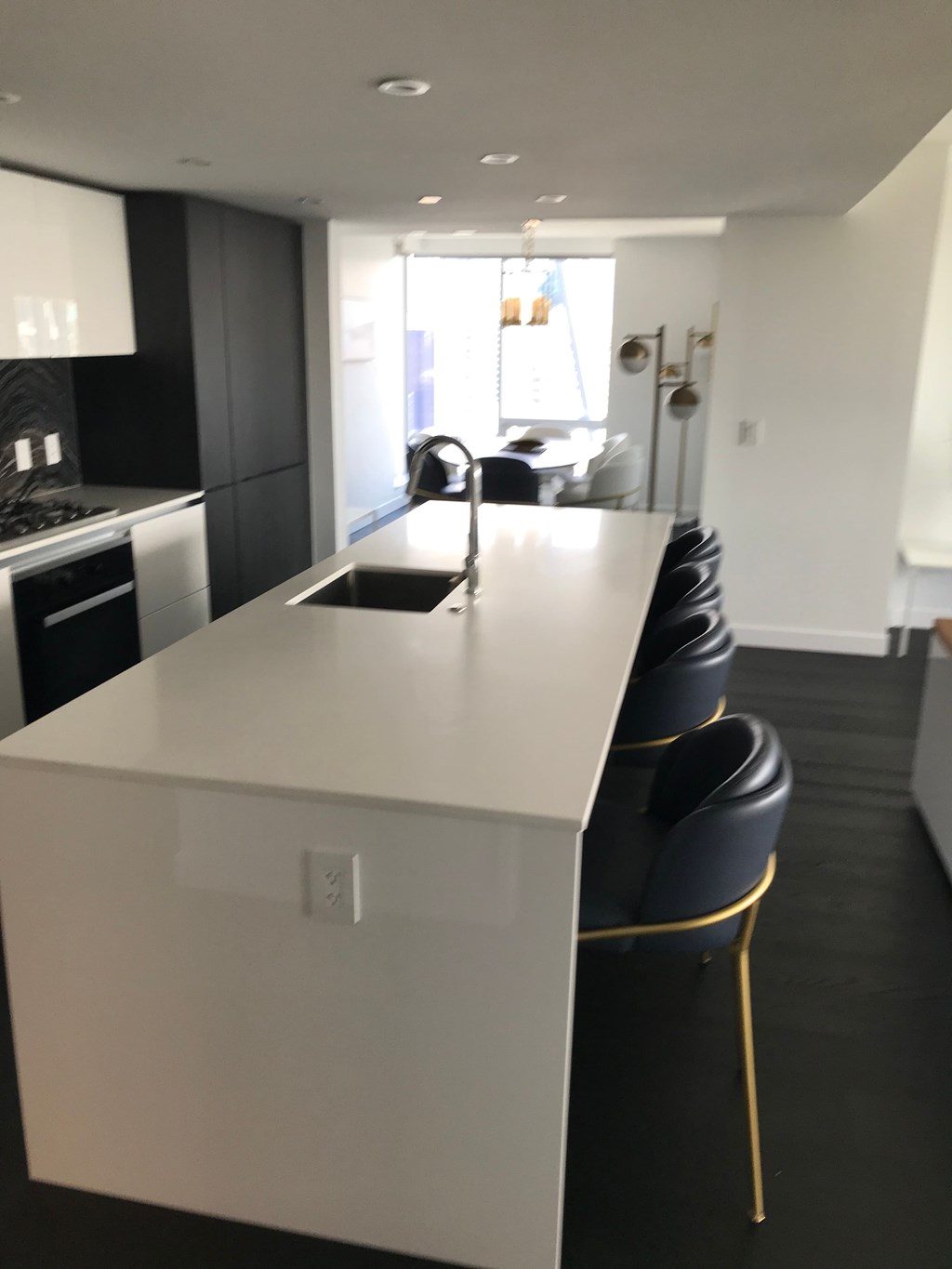 a kitchen with a white counter top and black chairs