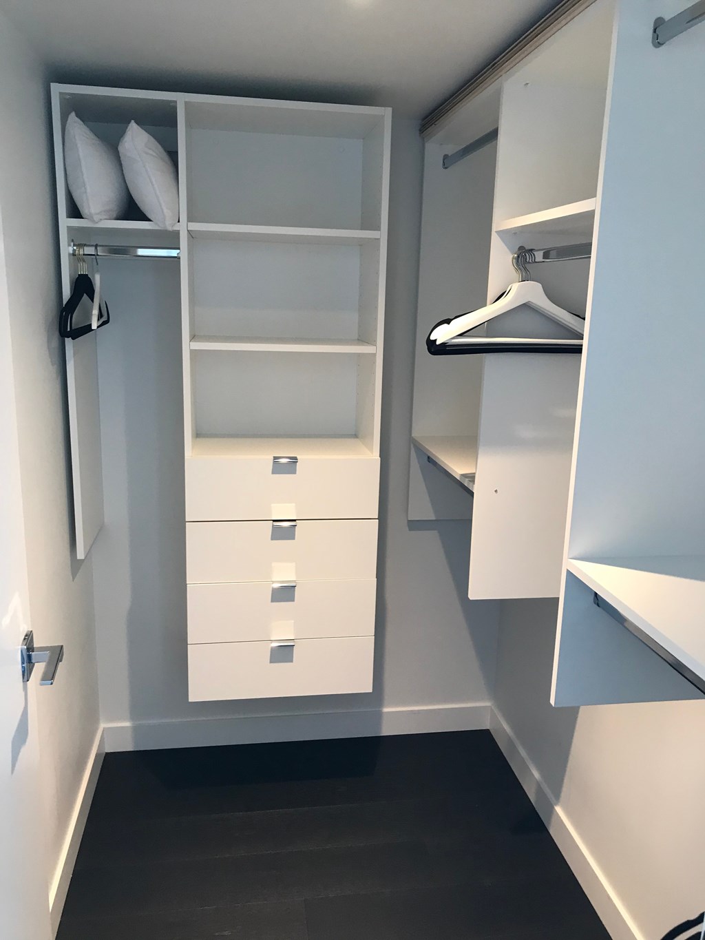 a walk in closet with white cabinets and shelves and drawers and a white drawer