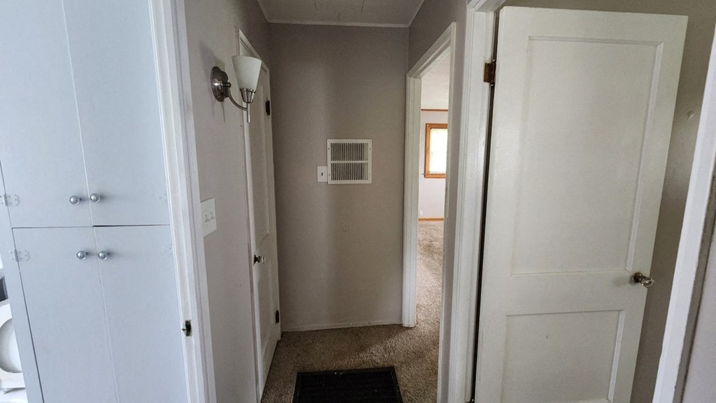 a hallway with a door to a bathroom and a closet
