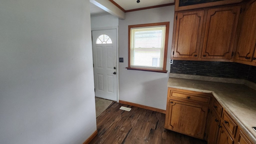 a kitchen with wooden floors and a white door and a window