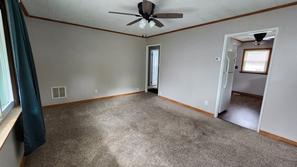 an empty living room with carpet and a ceiling fan