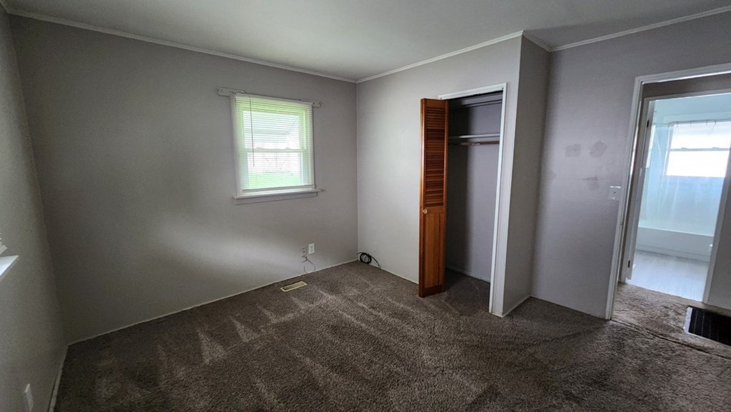 a bedroom with a door to a closet and a window